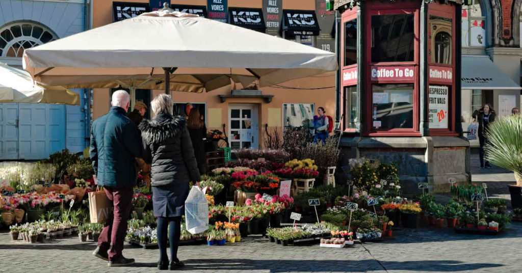 Ett äldre par framför en blomaffär en solig dag